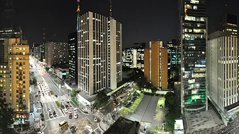 Vista noturna da Avenida Paulista com prédios iluminados.